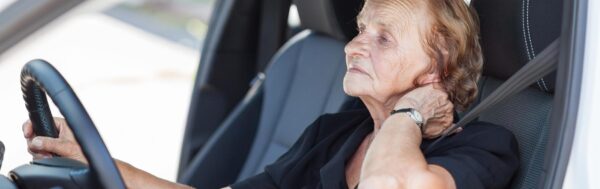 Senior woman driving with neck pain.