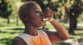 Woman using inhaler outside in a park