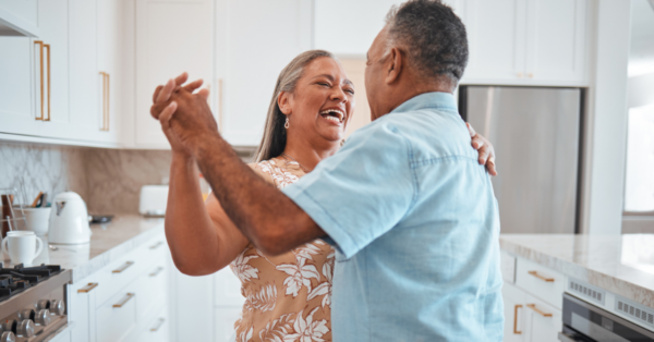 Happy senior couple, dance and laughing in kitchen at home.