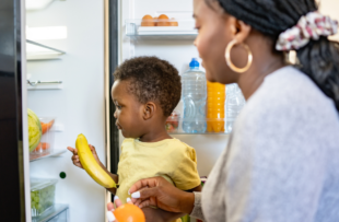 Cheerful African-American mother and son in the kitchen. Son helps a mother to bring in groceries after a grocery-shopping