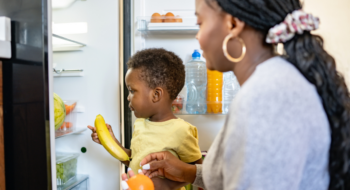 Cheerful African-American mother and son in the kitchen. Son helps a mother to bring in groceries after a grocery-shopping