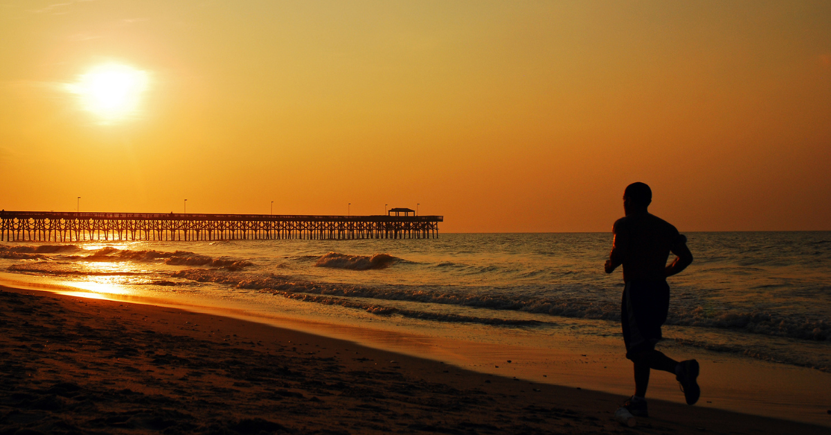 A Jogger runs towards the sun during a morning jog