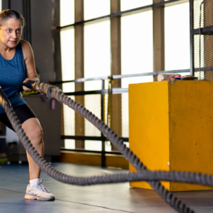 A woman working out with battle ropes at cross gym