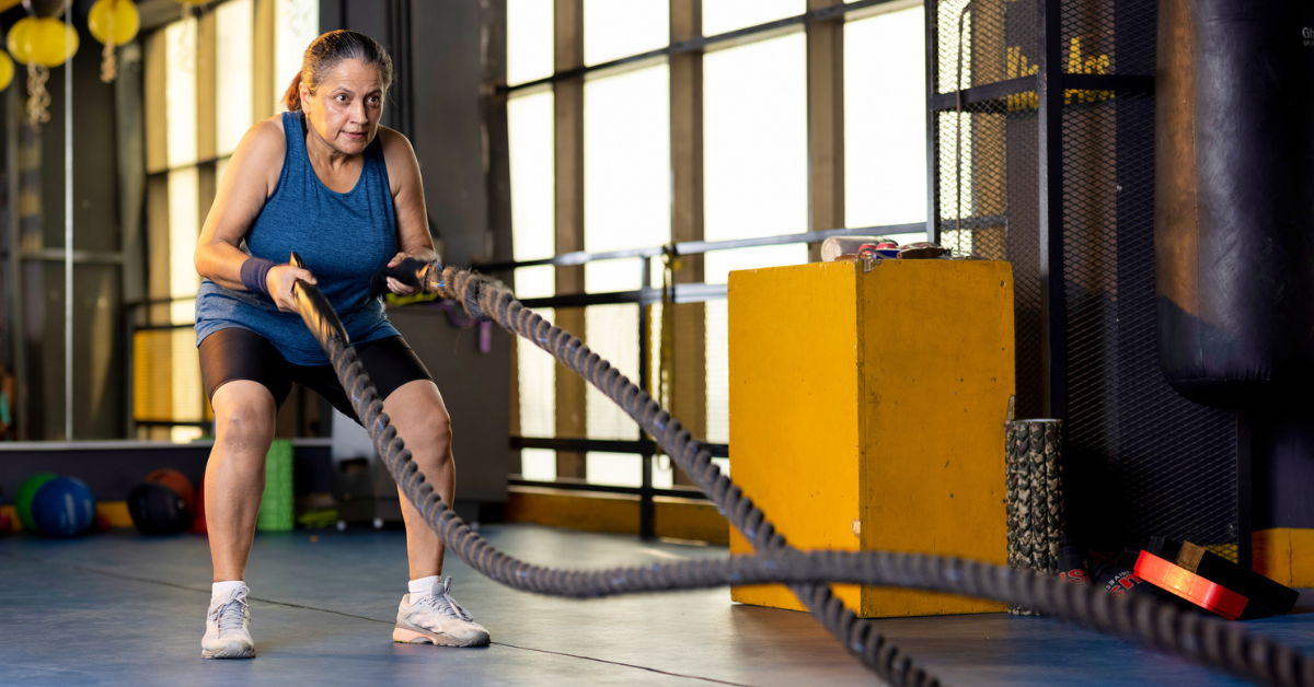 A woman working out with battle ropes at cross gym