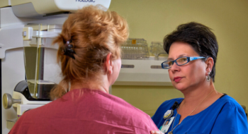 A mammography technician comforts a patient during her mammogram.