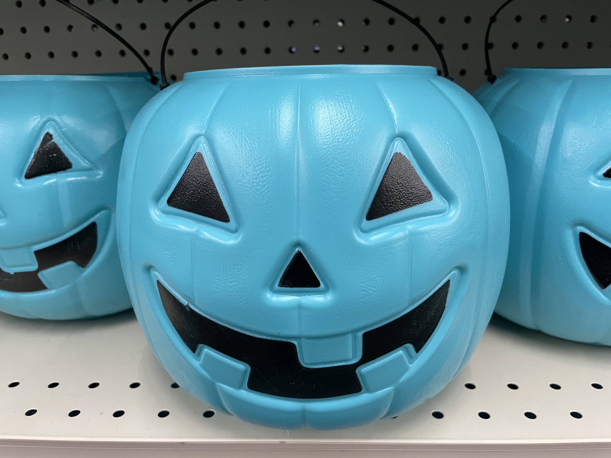 A teal pumpkin on a shelf.