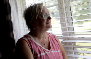 Tara Cook stares out of a window, smiling.