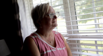 Tara Cook stares out of a window, smiling.