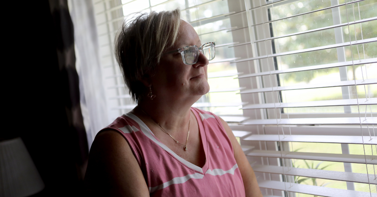 Tara Cook stares out of a window, smiling.