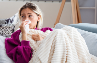 Young Woman Infected With Cold Blowing Her Nose In Handkerchief.