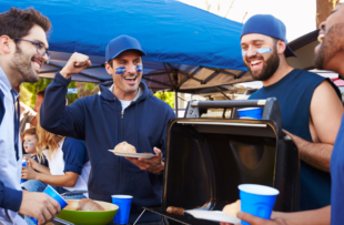 Group Of Male Sports Fans Tailgating In Stadium parking lot.