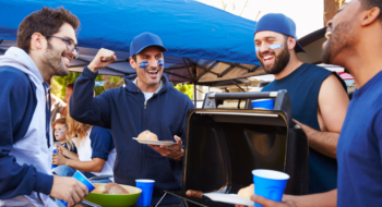 Group Of Male Sports Fans Tailgating In Stadium parking lot.