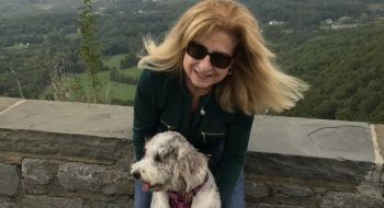 Patricia Jones standing on a mountain overlook with her dog.