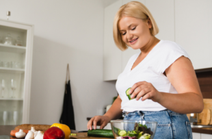 Young caucasian woman cooking making salad, healthy food.