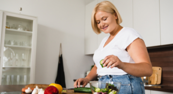 Young caucasian woman cooking making salad, healthy food.