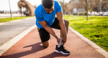 A runner grabbing his ankle on a track path.