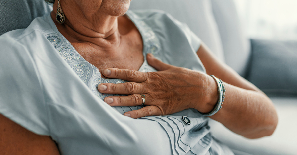 A woman wearing a blue shirt holds her chest in pain.