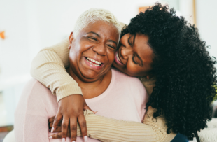 Elderly mother and daughter hugging and smiling.