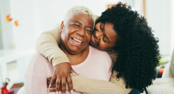 Elderly mother and daughter hugging and smiling.